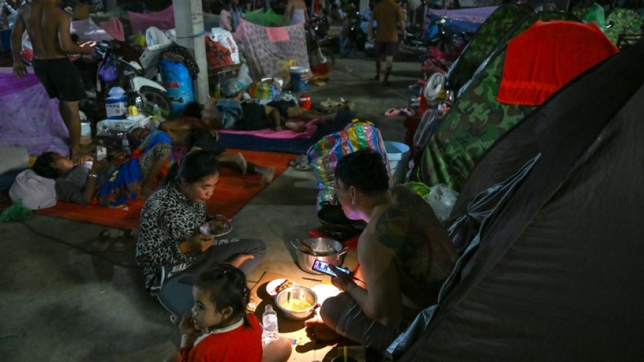 A displaced family uses a flashlight as they eat a meal at a temporary camp in Cambodia's Banteay Meanchey province, amid clashes along the border with Thailand
