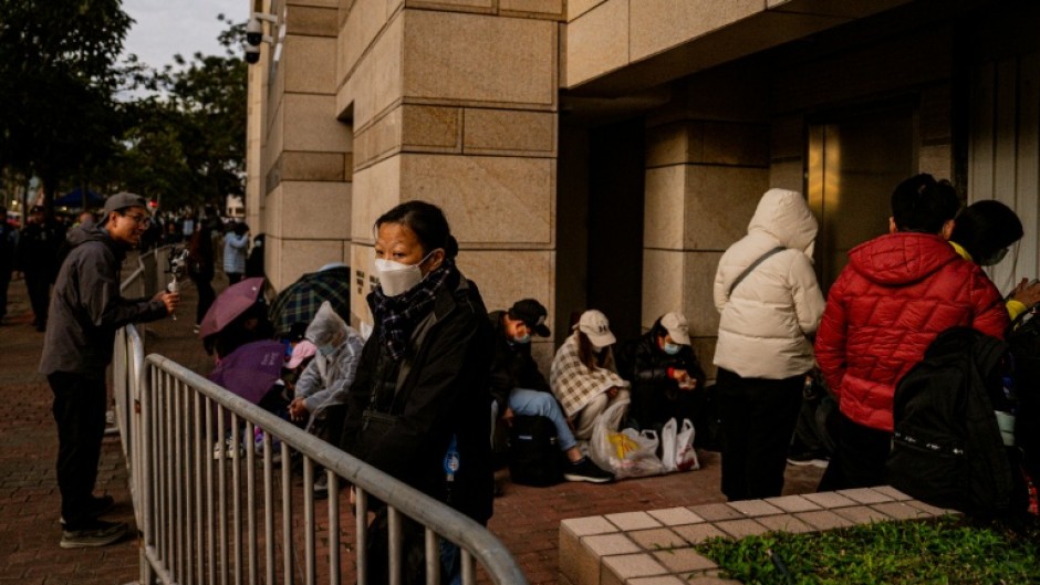 People wait in line outside the West Kowloon Law Courts building to hear the verdict in the national security trial of pro-democracy media tycoon Jimmy Lai in Hong Kong