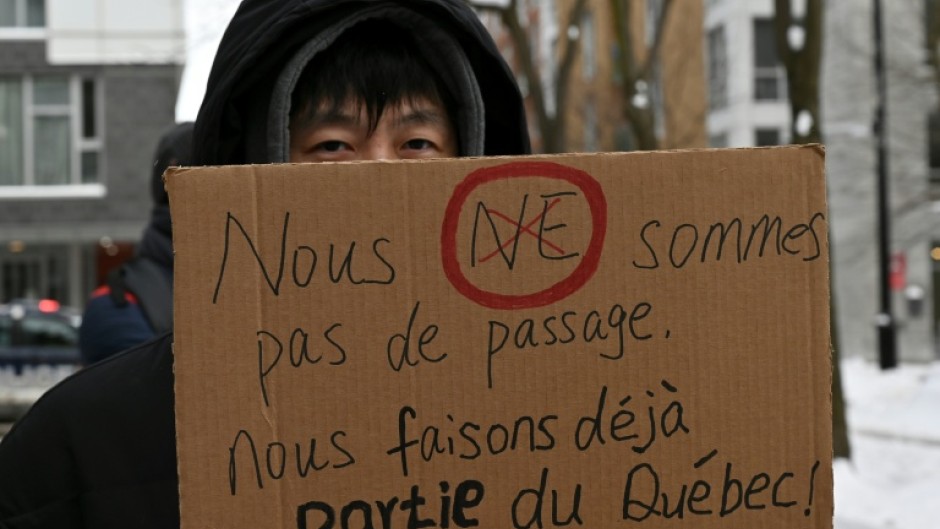 A pro-immigration demonstrator in Montreal, Canada holds a sign that reads in French: 'We're not just passing through, we're already part of Quebec'