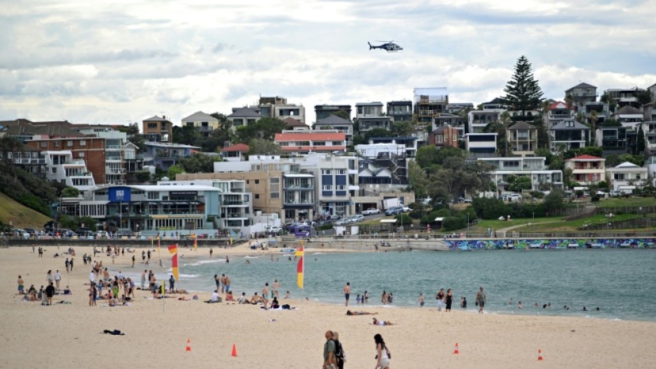 A police helicopter patrols over the Bondi Beach in Sydney as life gradually returns to normal following a deadly shooting attack
