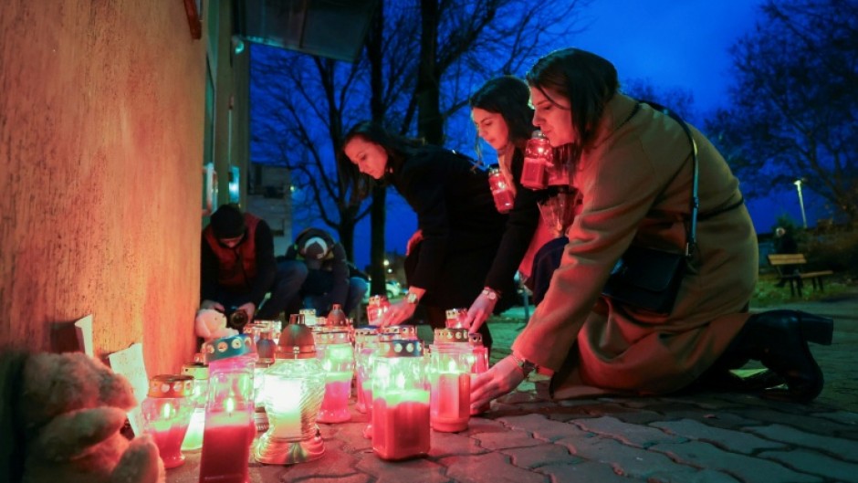 Women light candles at a makeshift memorial outside the Zagreb school where the stabbing happened