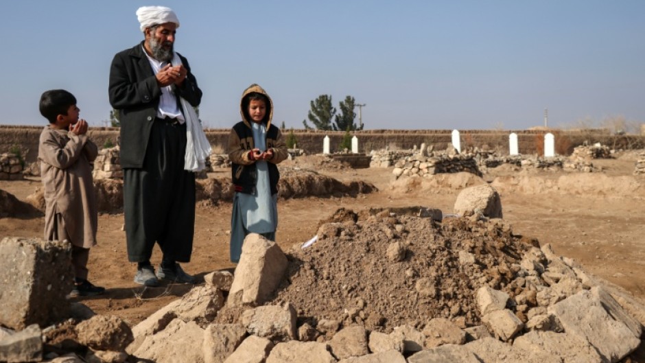 Gul Ahmad (centre) along with his deceased stepbrother Habibullah's son Waheed (right) and Saeed offering prayers over his grave in Ghunjan