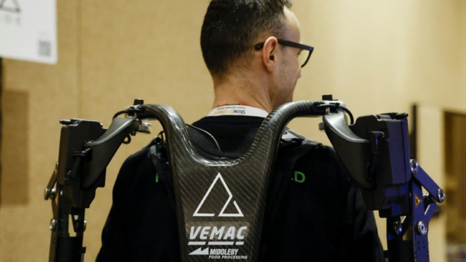 An exhibitor displays AGADE's Agadexo Lowback, its next-generation AI-driven industrial exoskeleton