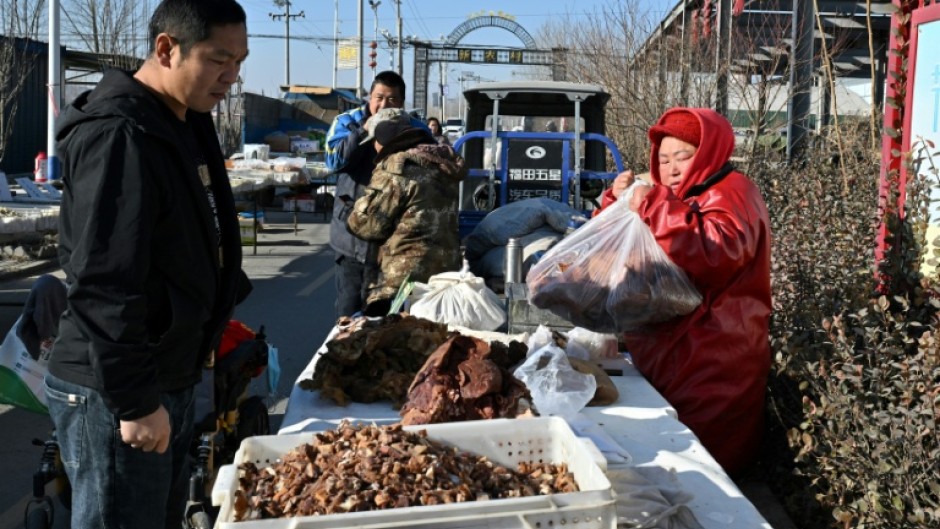 People trade at a traditional market in a neighbourhood affected by the heating subsidy policy, in Baoding city, northern China's Hebei province on January 7, 2026. Beijing has long mandated that dozens of northern areas wind down the use of coal-fired stoves in favour of electric and natural gas-powered systems