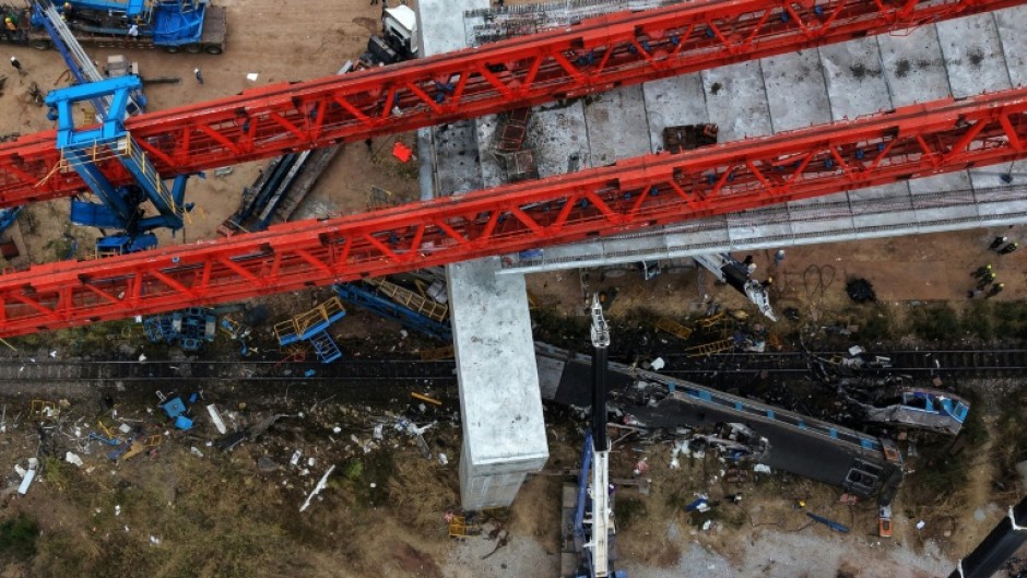 A massive crane was left resting on giant concrete pillars, while dozens of rescuers worked into the evening, searching for missing people in mangled train carriages
