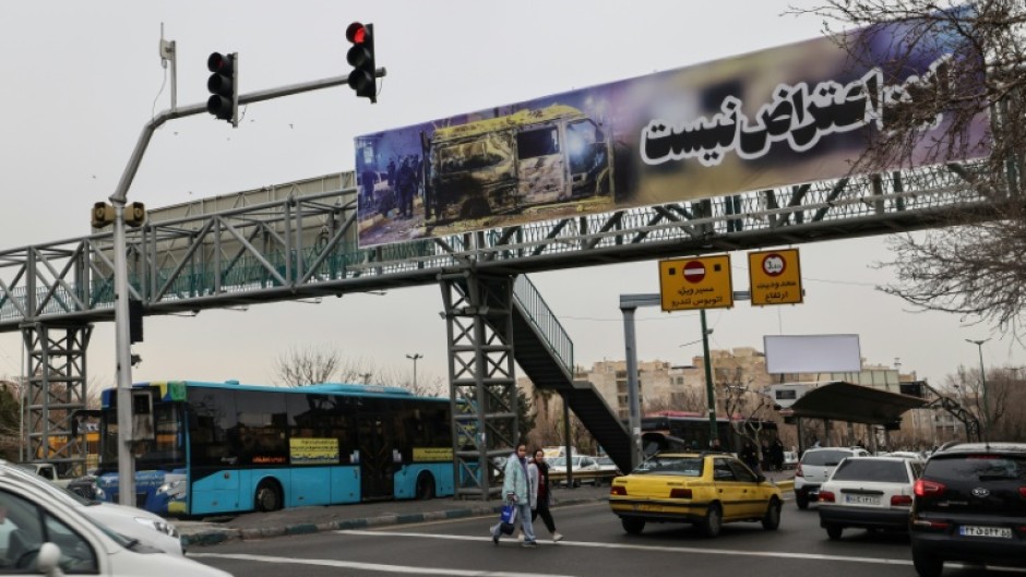Cars drive under a banner that reads "This is not a protest" in Tehran