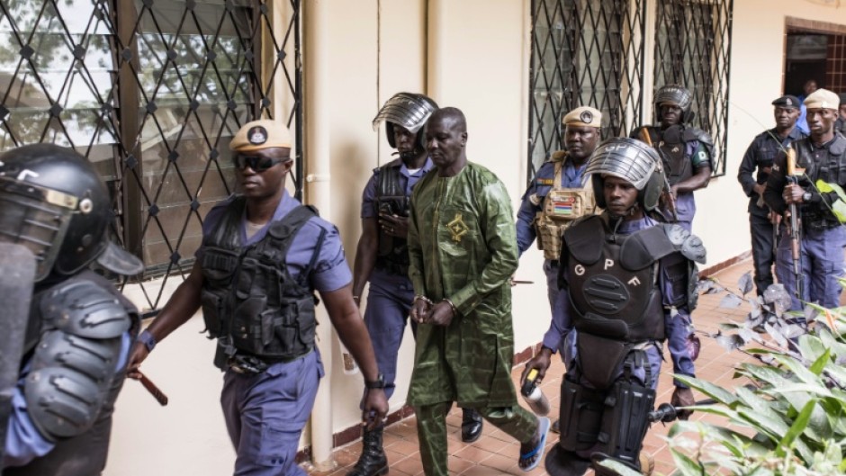 Security officers escort Sanna Manjang (C), a former member of The Gambia's 'Junglers' death squad, as he arrives at court