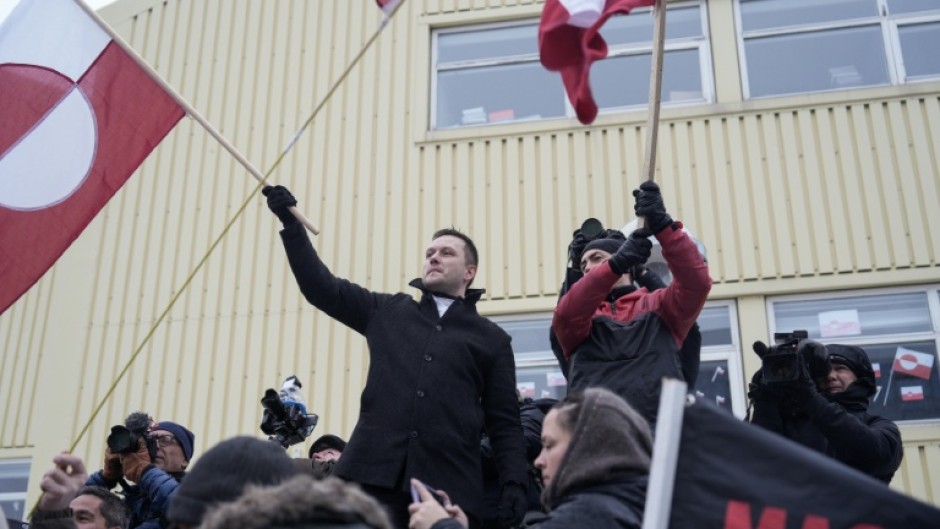Greenland's prime minister Jens-Frederik Nielsen (L) holds a Greenlandic flag at a demonstration against US President Donald Trump's wish to take over the territory
