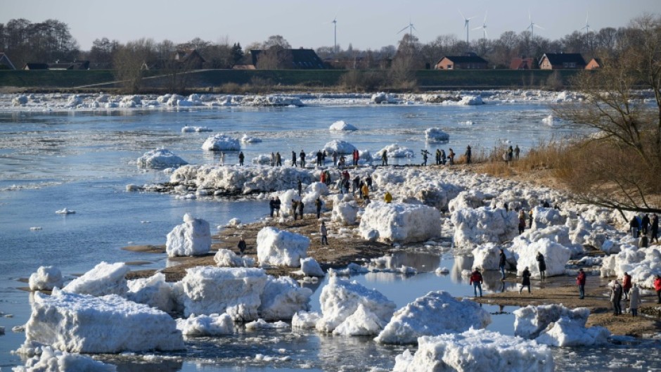 Onlookers make their way through large chunks of ice washed up along the banks of the Elbe river near Geesthacht, northern Germany, on January 19, 2026.