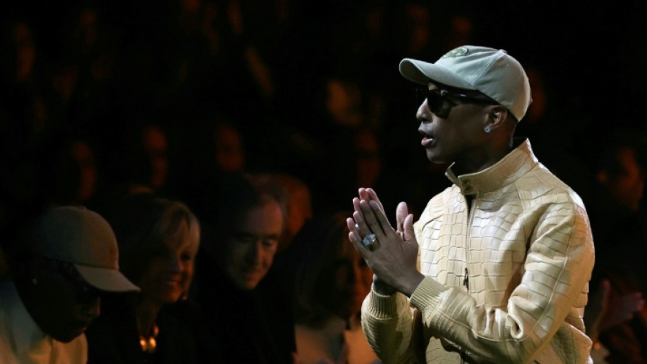 US rapper and fashion designer Pharrell Williams greets the audience at the end of the Louis Vuitton show