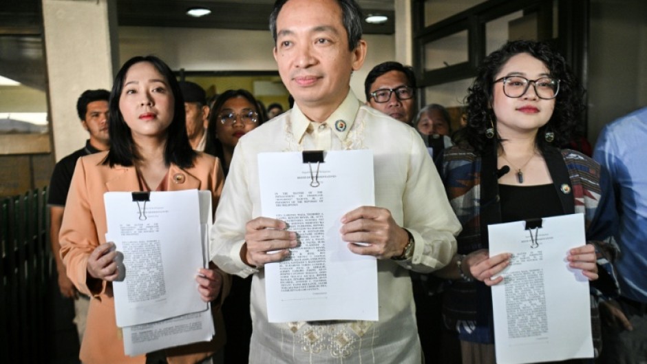 Lawmakers Sara Elago, Antonio Tinio and Louise Co show the impeachment complaint against Philippine President Ferdinand Marcos at the House of Representatives on Thursday