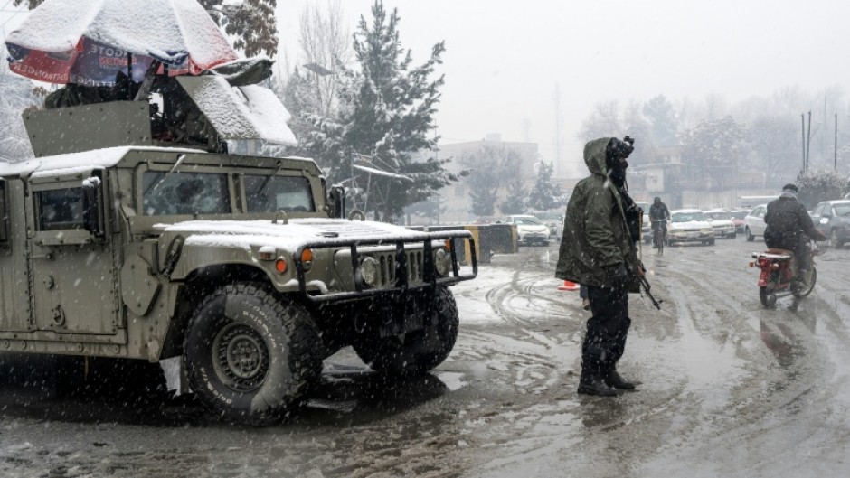 A Taliban security personnel stands guard at a checkpoint during snowfall in Kabul on January 22, 2026.