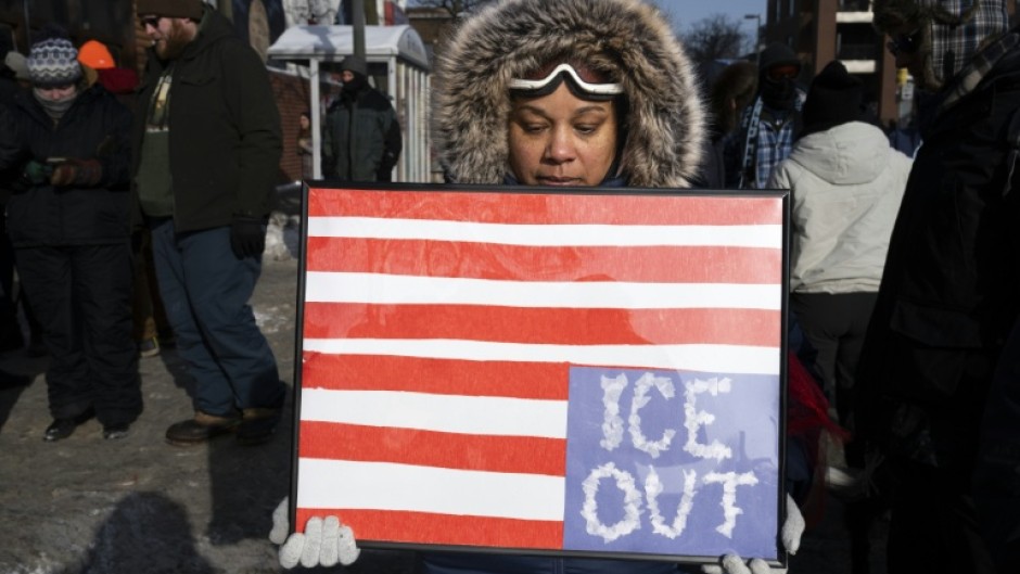 A woman holds a placard with an upside down American flag to protest violence by the ICE immigration agency in Minneapolis