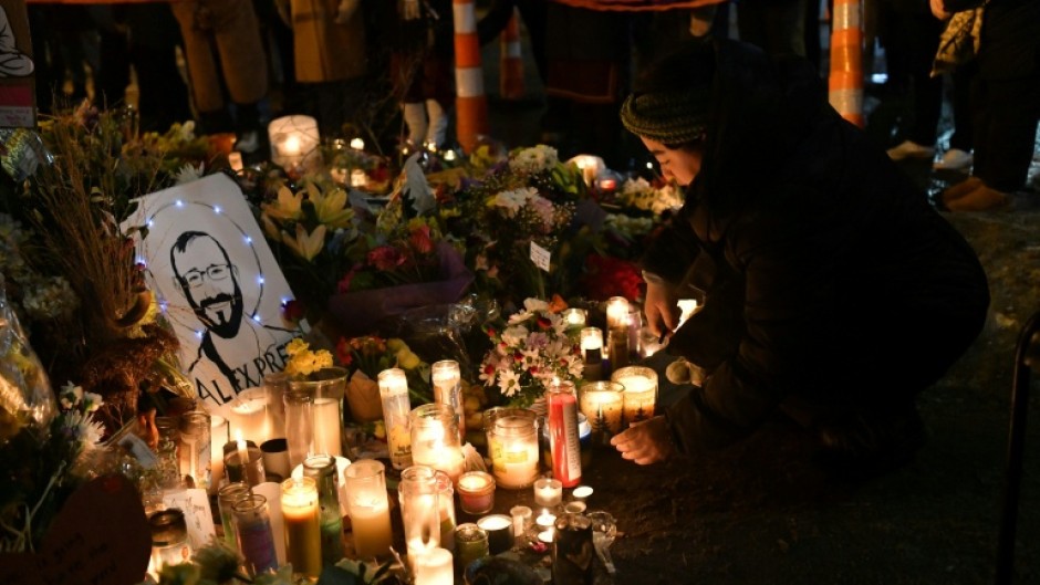 A woman lights a candle while mourning at a memorial where Alex Pretti was shot dead by federal immigration agents in Minneapolis