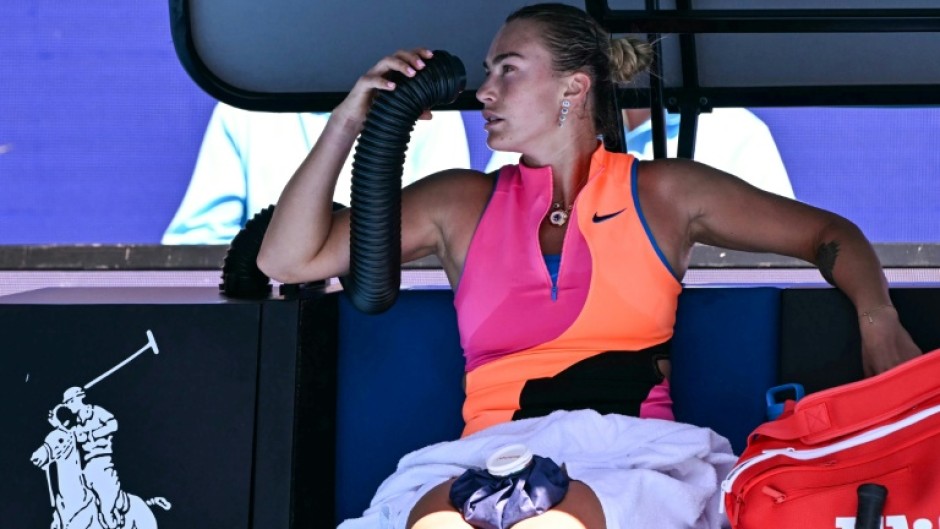 Aryna Sabalenka holds an air conditioning pipe to cool down during her women's singles quarter-final
