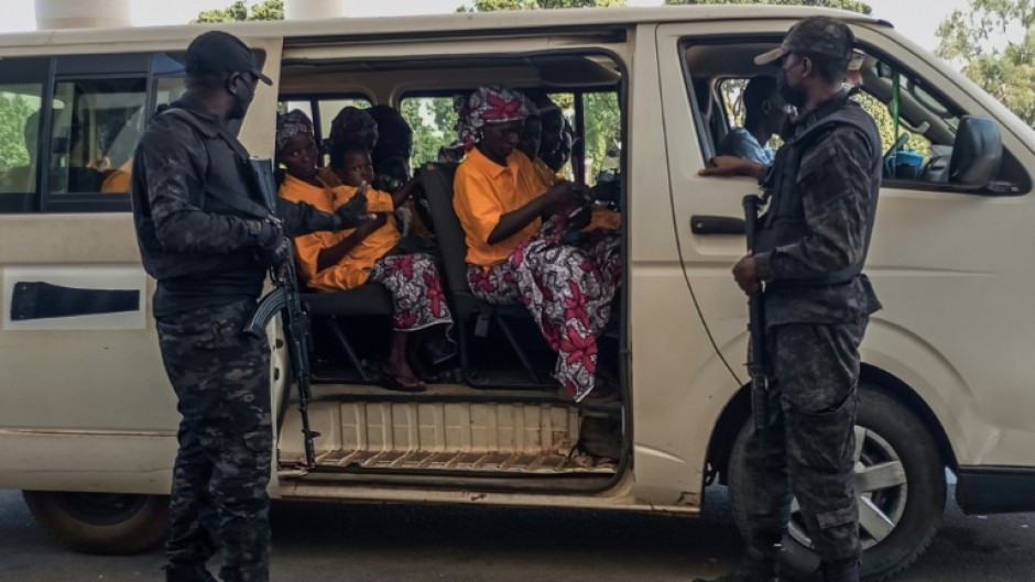 Security officers stand guard next to a bus carrying freed worshippers in northern Nigeria, where gunmen kidnapped Christians in coordinated attacks on three churches in January