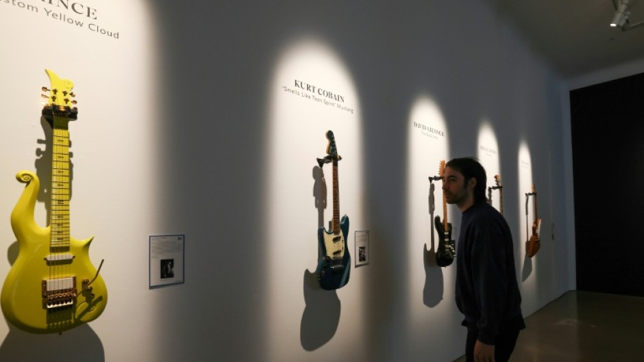 A visitor looks at Prince’s Andy Beech custom Yellow Cloud guitar (L) and Kurt Cobain’s 1966 Fender Mustang guitar ahead of an auction at Christie’s