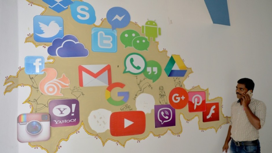 A man passes by a mural depicting various social media apps in Bangalore on March 22, 2018