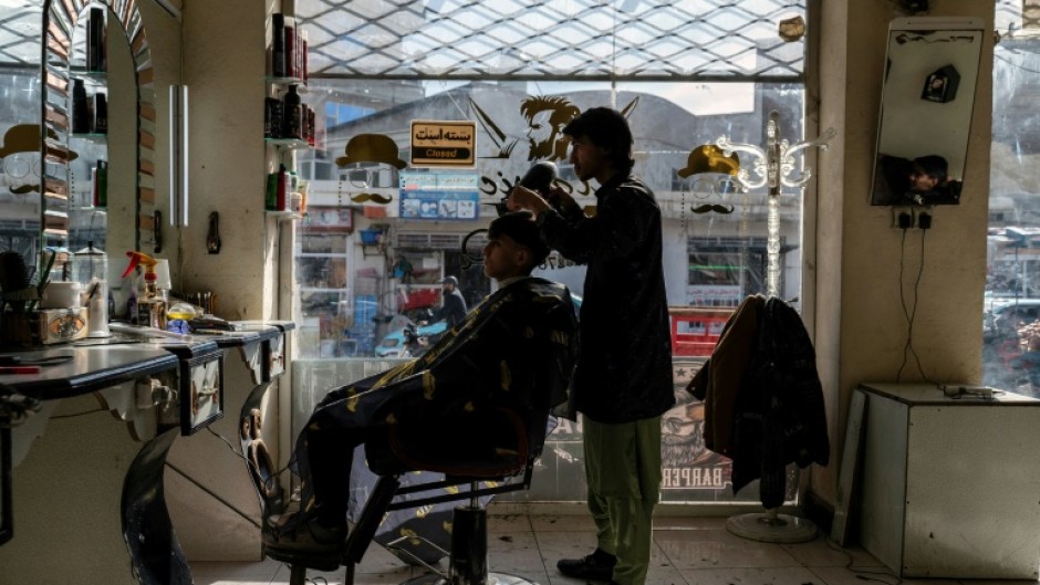 An Afghan barber attends to a customer at a salon in Kabul
