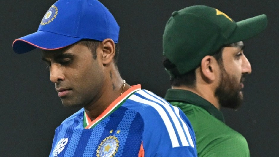 India's captain Suryakumar Yadav (L) walks past his Pakistan counterpart Salman Agha after the toss