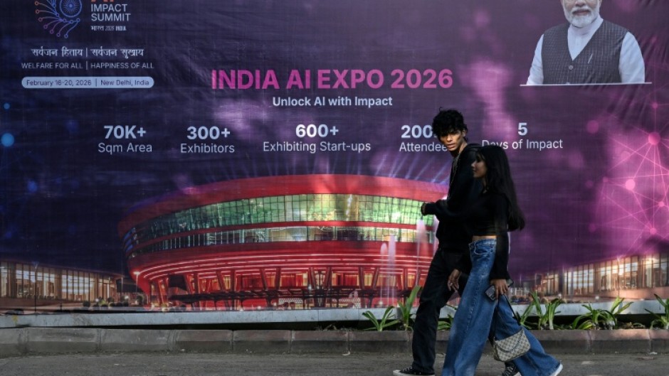 Commuters walk past a billboard for an AI Expo in New Delhi