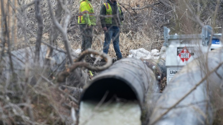 Emergency workers look on as raw sewage flows out of a drainage pipe into the C&O Canal near Cabin John, Maryland, after more than 200 million gallons of wastewater spilled into the Potomac River