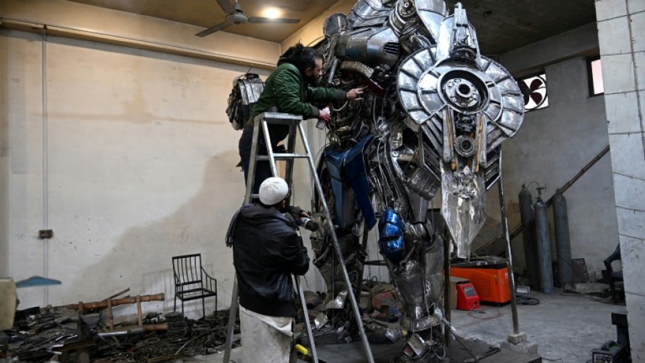 Sculptor Ehtisham Jadoon spray paints a model of Optimus Prime, a film character from Transformers, made from scrap metal at his studio