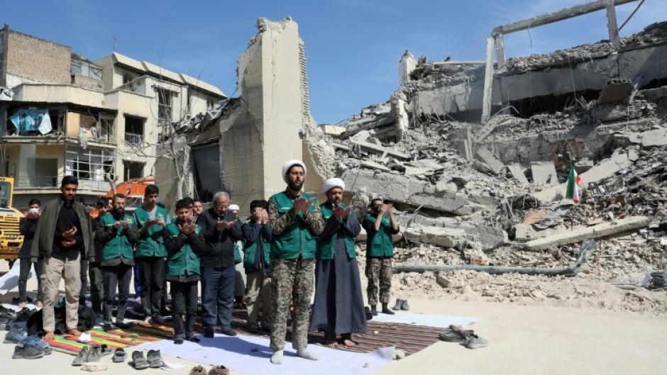 Iranian clerics and volunteers from the Bsij military who are helping clear the streets pray next to the rubble of a police station destroyed in airstrikes in central Tehran, on March 4, 2026.