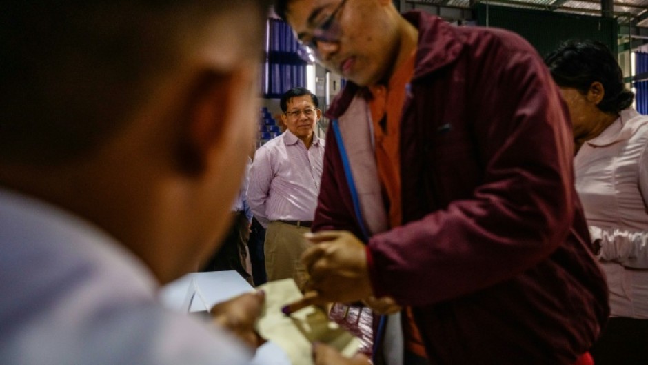 Military chief Min Aung Hlaing (back C) watches a voter ink their finger as he visits a polling station during the final phase of Myanmar's general election in January