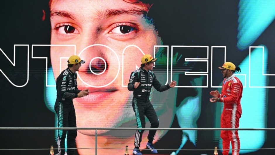 Winner Mercedes' Italian driver Kimi Antonelli (C), second-placed Mercedes' British driver George Russell (L) and third-placed Ferrari's British driver Lewis Hamilton (R) celebrate on the poidum after the Formula One Chinese Grand Prix at the Shanghai International Circuit in Shanghai on March 15, 2026.