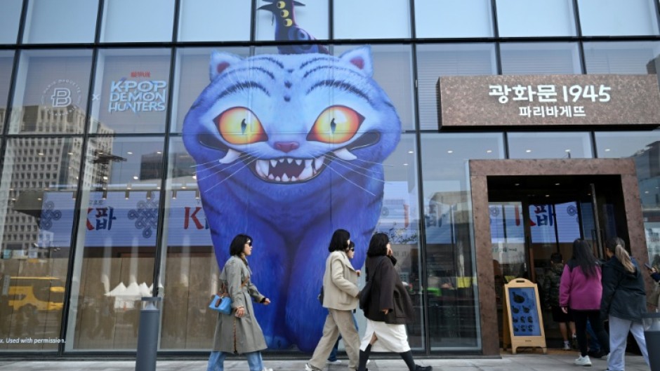 People walk past a glass wall displaying animal characters from Netflix series "Kpop Demon Hunters" at a bakery in Seoul on March 17, 2026