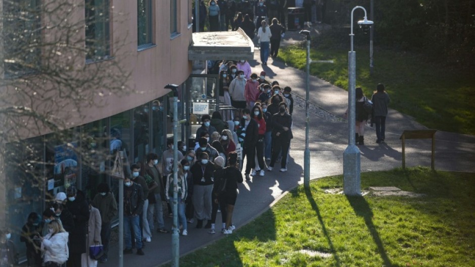 Students wearing face masks queue up for vaccines at the University of Kent in Canterbury, southeast England amid a deadly outbreak of meningitis