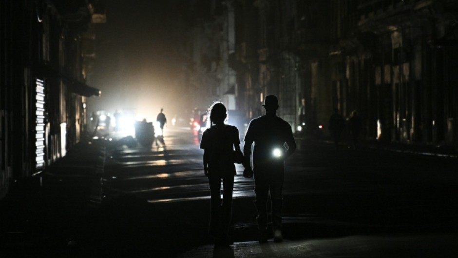 People walk on a street without power during a nationwide blackout in Havana on March 21, 2026