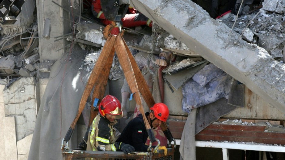 Firefighters try to recover the body of a victim in a damaged building in southern Tehran