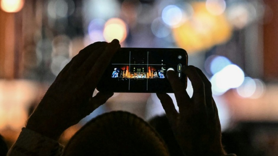 A fan takes photos at an event in London to mark the 50th birthday of US tech giant Apple