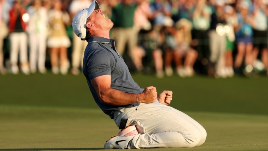 Rory McIlroy celebrates winning the 2025 Masters after falling to his knees on the 18th green having just completed a career grand slam