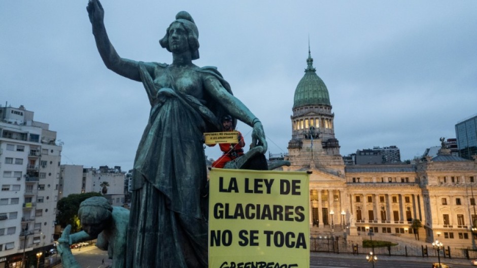 A Greenpeace activist unfurls a banner reading 'Hands off the Glaciers Law' outside Argentina's parliament ahead of a vote by MPs on an amendment watering down glacier protections