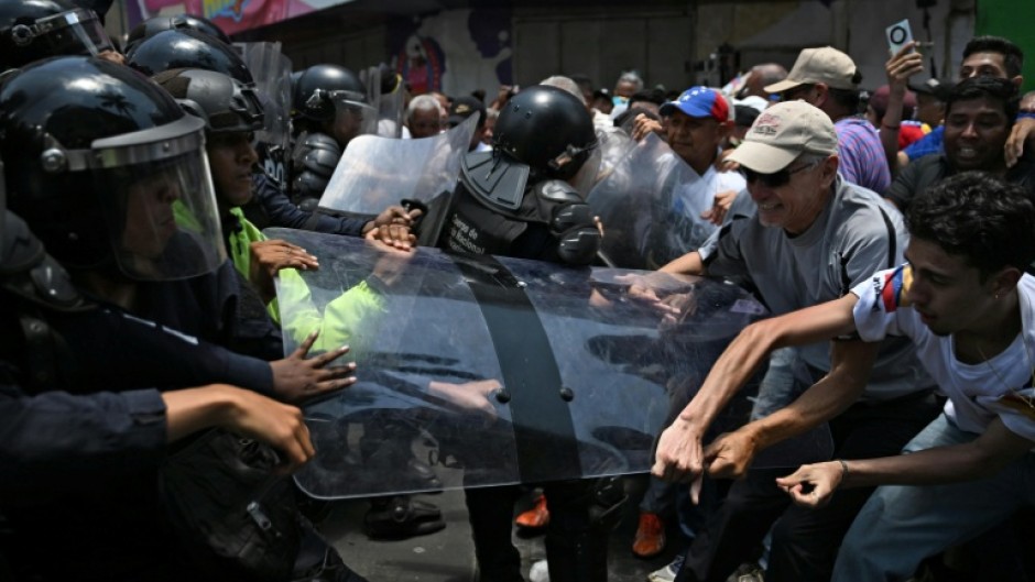 Opponents to the government of Venezuelan interim President Delcy Rodriguez clash with the police as they demonstrate in demand of salary and pension raises in Caracas on April 8, 2026