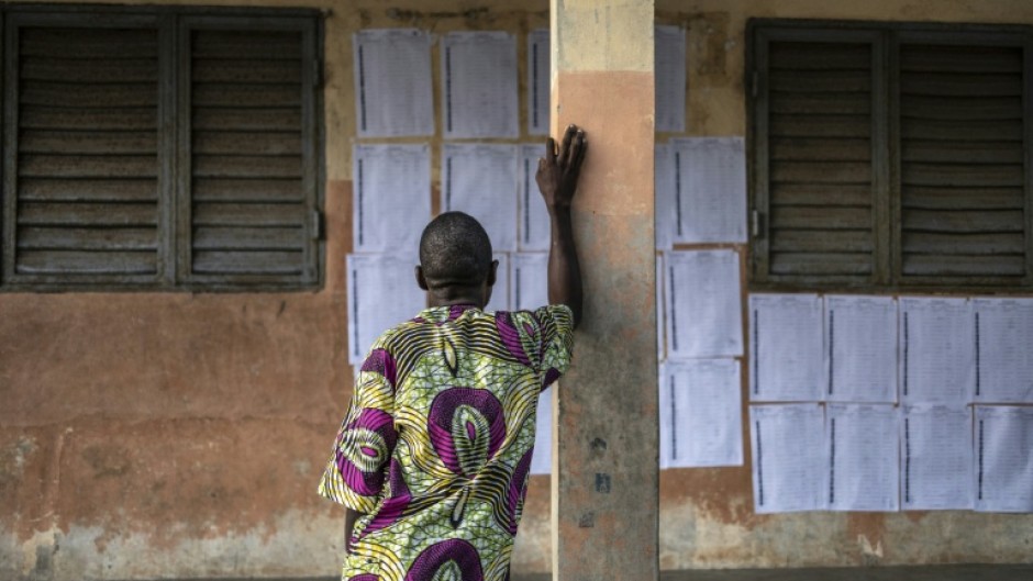 A voter looks for his name on the electoral roll at a primary school serving as a polling station in Cotonou, Benin