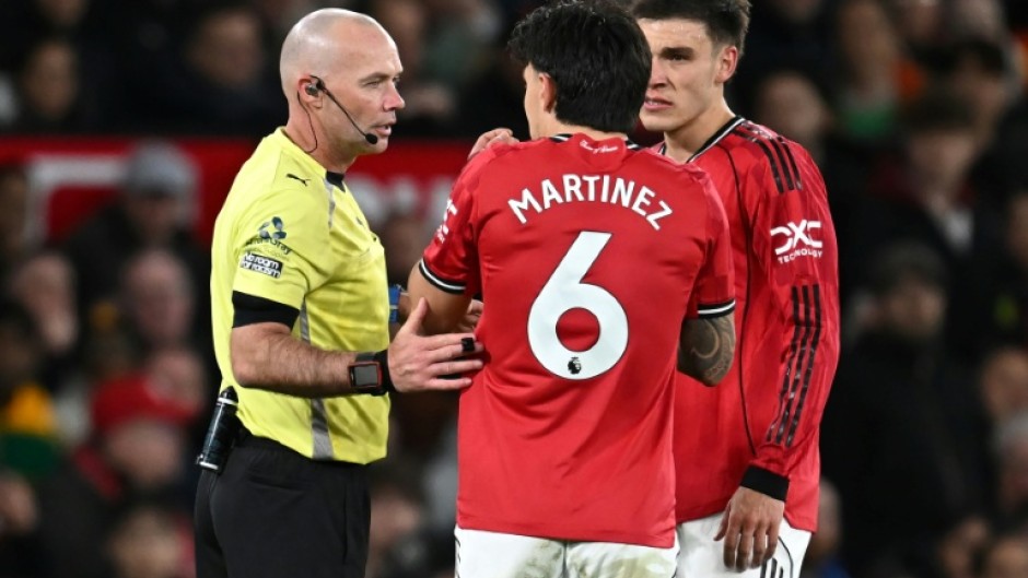 Referee Paul Tierney speaks with Manchester United defender Lisandro Martinez (C)