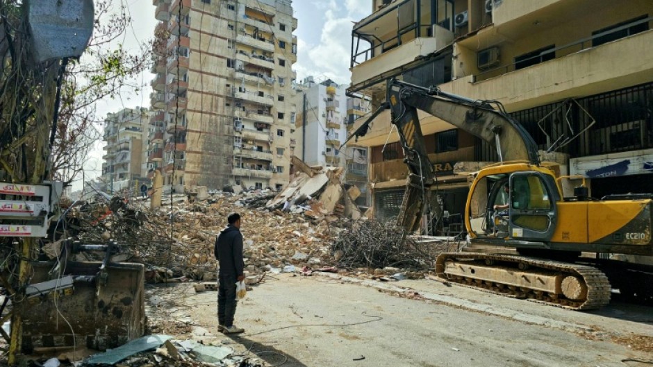 A bulldozer clears the rubble from the site of an Israeli airstrike as people return to Beirut's southern suburbs