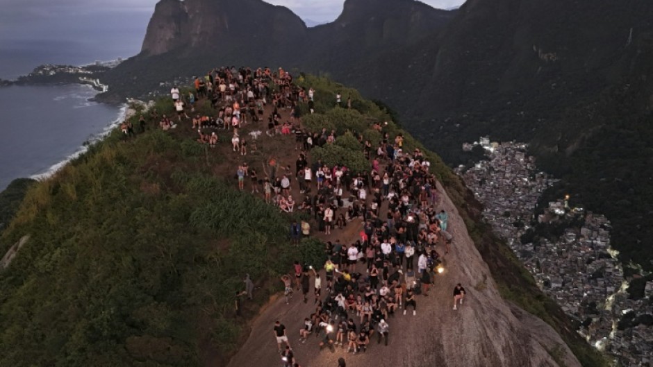 Tourists watch the sunrise from Morro Dois Irmaos above the Vidigal favela