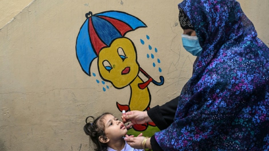 A healthcare worker administers polio drops during a door-to-door poliovirus eradication campaign in Lahore