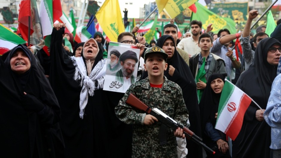 A young enthusiast in military attire holds a mock rifle during a rally to show support for Iran's new supreme leader, Ayatollah Mojataba Khamenei, in Tehran