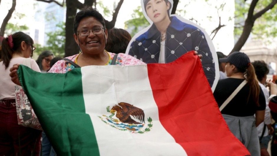 Una mujer muestra una bandera de México junto a una figura de cartón de J-Hope, cantante surcoreano de K-pop del grupo BTS, durante una reunión de fans en la Ciudad de México el 3 de mayo de 2026.