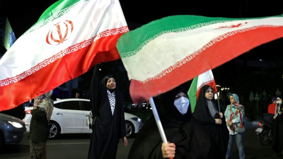 Women hold Iran's national flags during an anti-US and Israel protest in Tehran