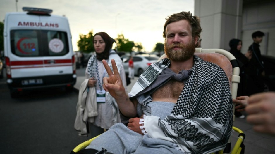A member of the Global Sumud Flotilla arrested and deported by Israel gives the V-sign as he is brought out of a terminal at Istanbul Airport