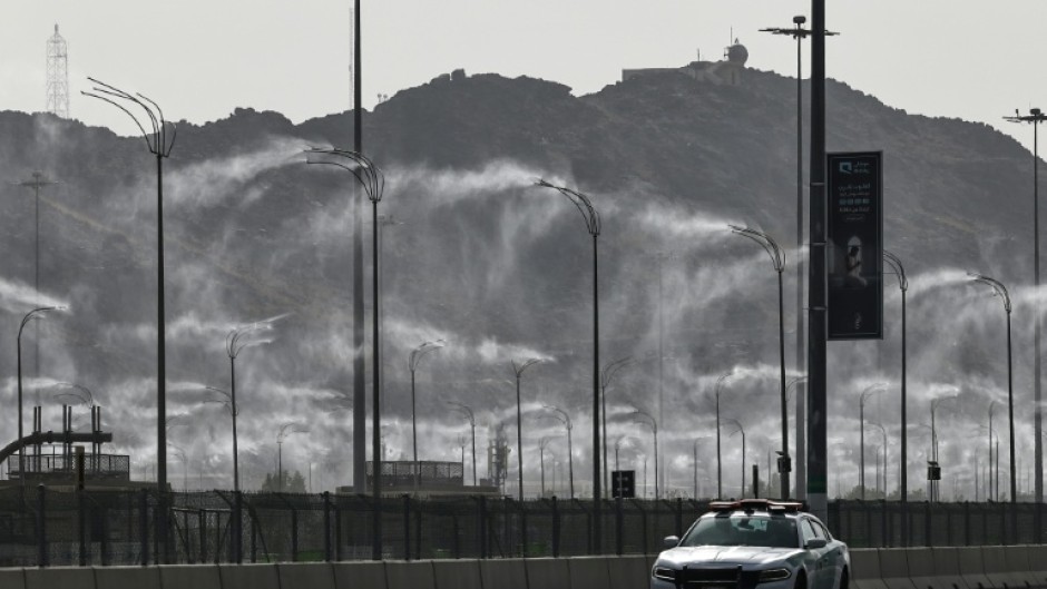 A police car drives past water-mist fans in Mecca ahead of the hajj pilgrimage when temperatures could reach 47 degrees Celsius