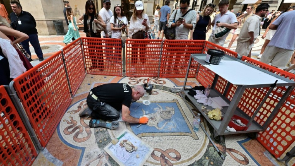 Restorer Gianluca Galli works on the mosaic of the bull during the restoration in the Galleria Vittorio Emanuele II
