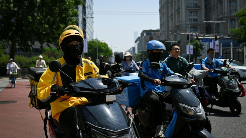 Food delivery workers on their vehicles on a street in Beijing